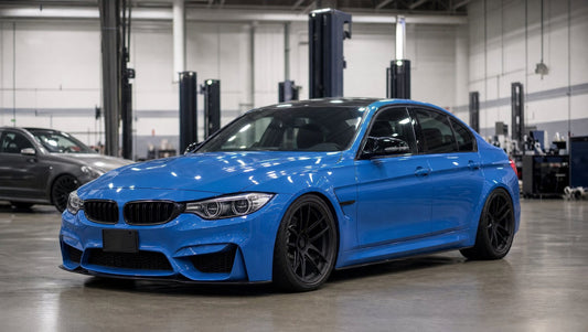 Yas Marina Blue BMW F80 M3 sedan on black wheels in a performance shop