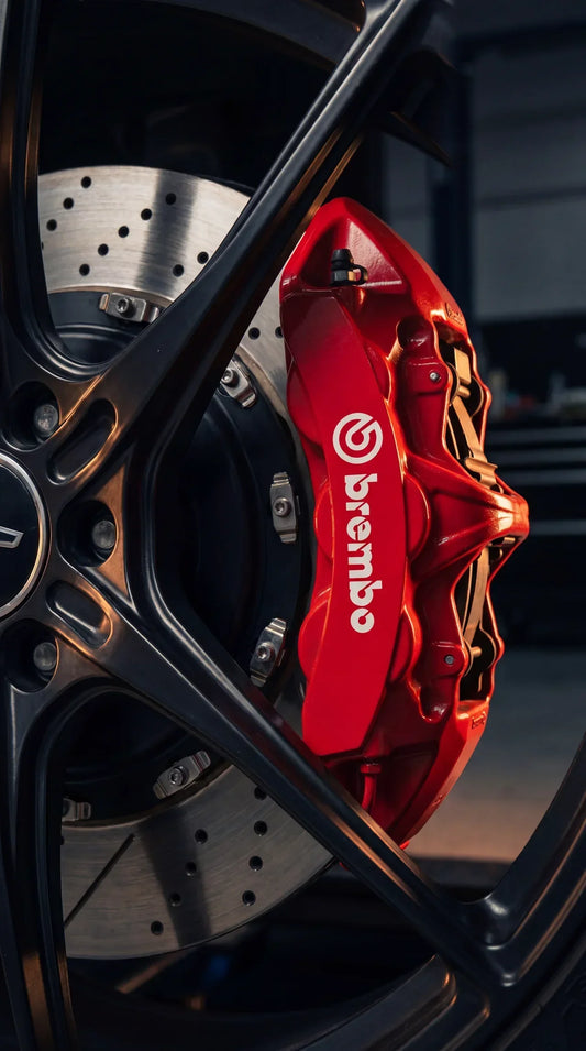 Red Brembo GT six-piston big brake kit caliper and cross-drilled rotor mounted behind a performance wheel
