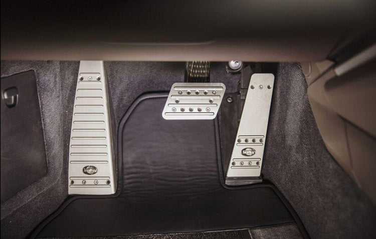 A close up view of TECHART Aluminum Anodized Foot Rest w/ TechArt Logo Porsche 992 Carrera / Targa / Turbo LHD fitted in a car
