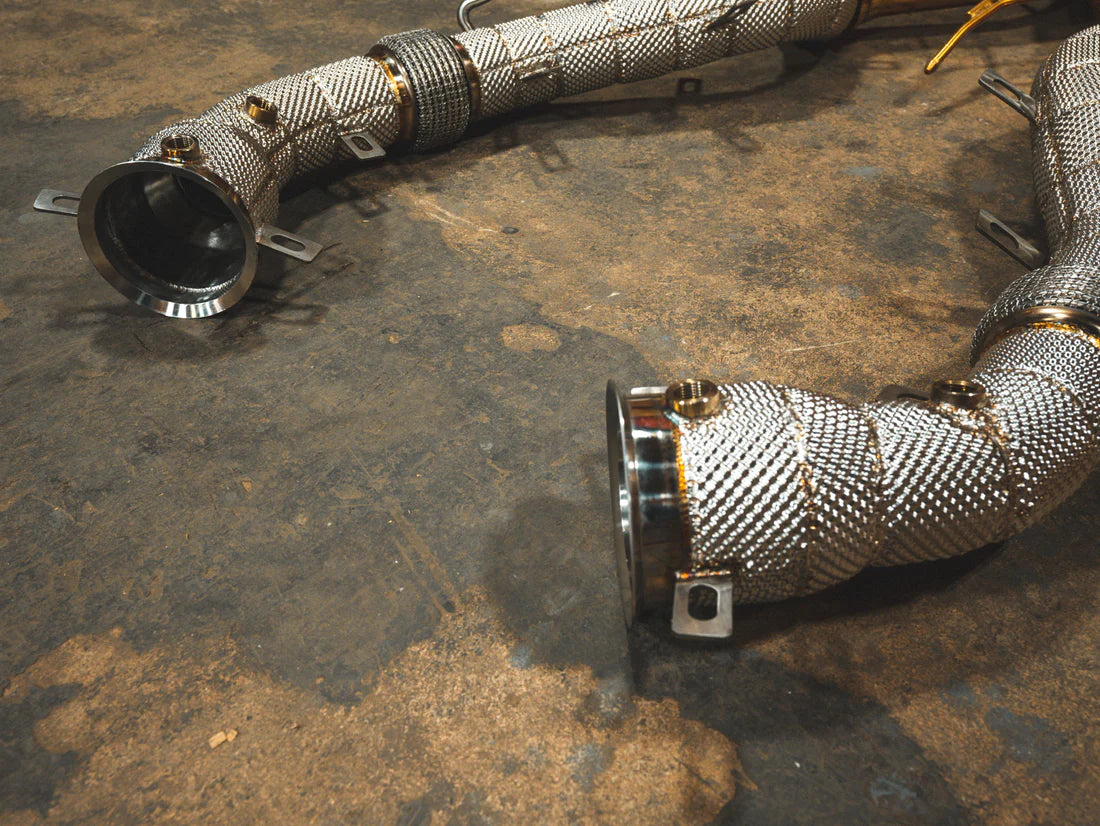 A close up view of Valvetronic Designs Sport Exhaust System's free flow front pipes on the ground (for Mclaren P1).