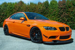 A side wide view of AUTOTECKNIC FRONT BUMPER DRY CARBON CANARD SET - BMW E9X M3 2007-2013 fitted on an orange car