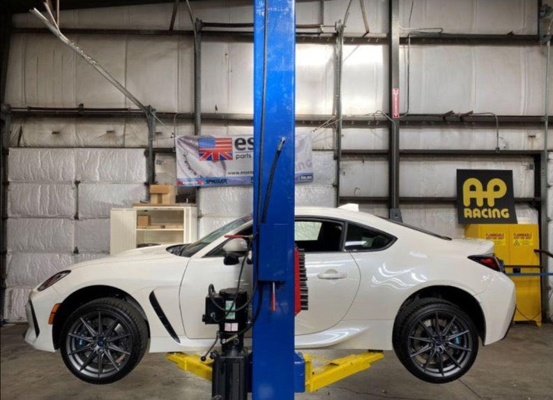 A wide view of a white car and its wheels from the side fitted with AP Racing by Essex Radi-CAL Competition Brake Kit (Front CP9660/372mm) - Subaru BRZ, Scion FR-S & Toyota GT86/GR86 2013+