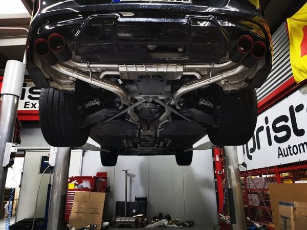 Wide view of Capristo Exhaust System, OPF Delete Mid Pipes, and Carbon Fiber Tips for BMW X5/6M GX 2018+ fitted inside a car