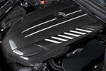 Close-up of the Dinan carbon fiber engine cover installed on a Toyota GR Supra engine, showing the precise fitment around the oil cap and seamless integration with the factory engine bay.