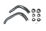 Two curved carbon fiber charge pipes with metal couplers, clamps, and small hardware components on white background - Eventuri charge pipes for BMW M3