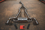 Wide overhead shot of the full stainless steel valved exhaust system laid out on a concrete floor with the red controller box and wiring harnesses.
