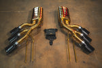 Overhead view of two gold-finish side-exit mufflers with triple black exhaust tips and a central valve controller unit.