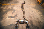 Full view of the Valvetronic Designs Titanium Equal Length Valved Sport Exhaust System with burnt blue quad tips laid out on a concrete floor.