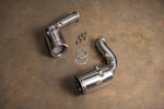 A pair of Valvetronic Designs 400 Cell Catted Downpipes for a 2019-2022 Lamborghini Urus, displayed on a concrete floor with accompanying mounting hardware and gaskets.