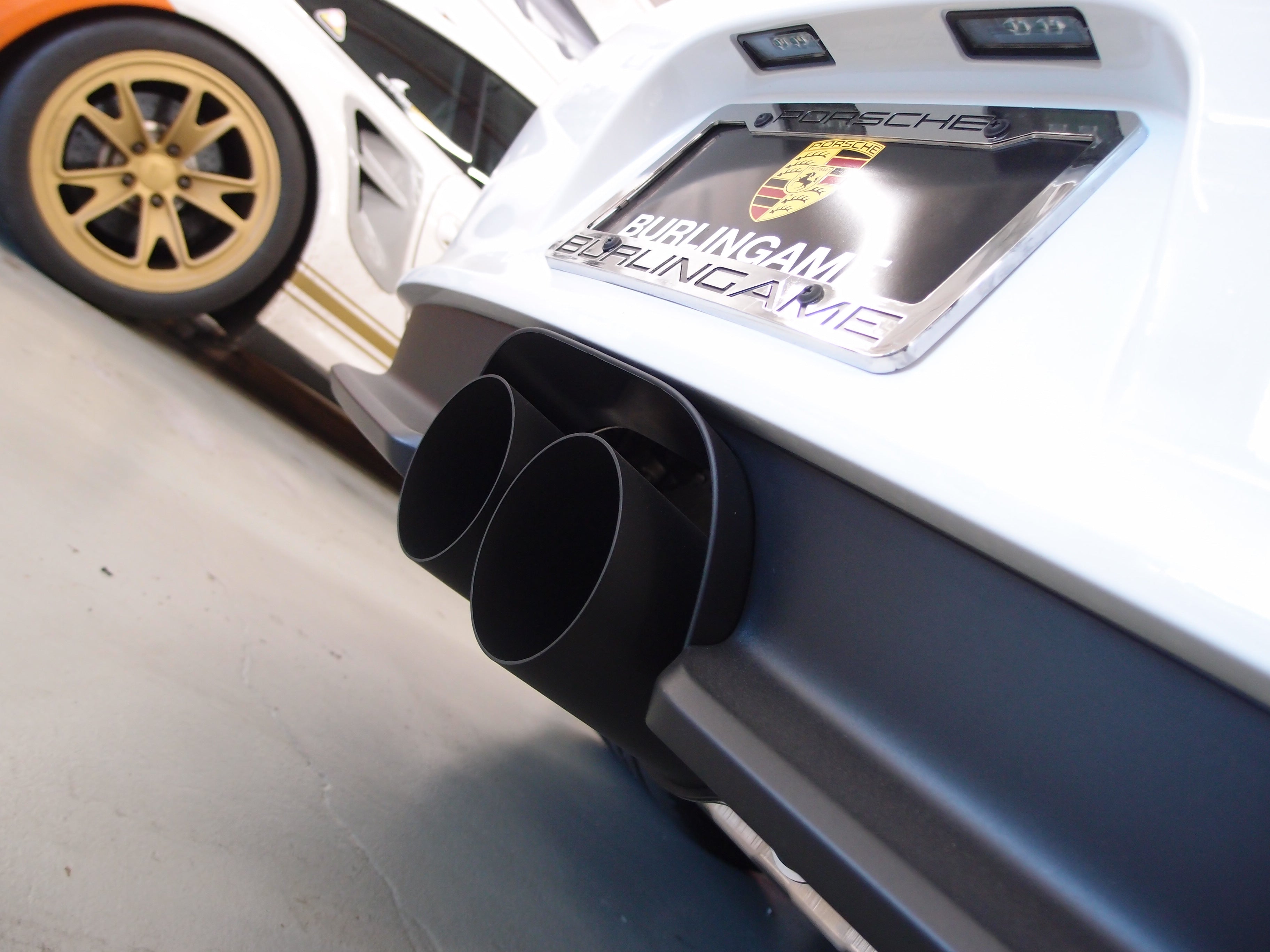 A close up view of Shark Werks 100mm Exhaust Tips for Porsche 991 / 991.2 GT3 / RS / R fitted on a car from behind 