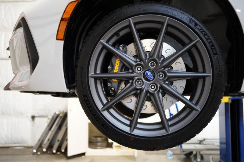A front view of a white car with the front wheel fitted with AP Racing by Essex Competition Endurance Brake Kit (Front CP8350/325mm)- Subaru BRZ, Scion FR-S & Toyota GT86/GR86 2013+