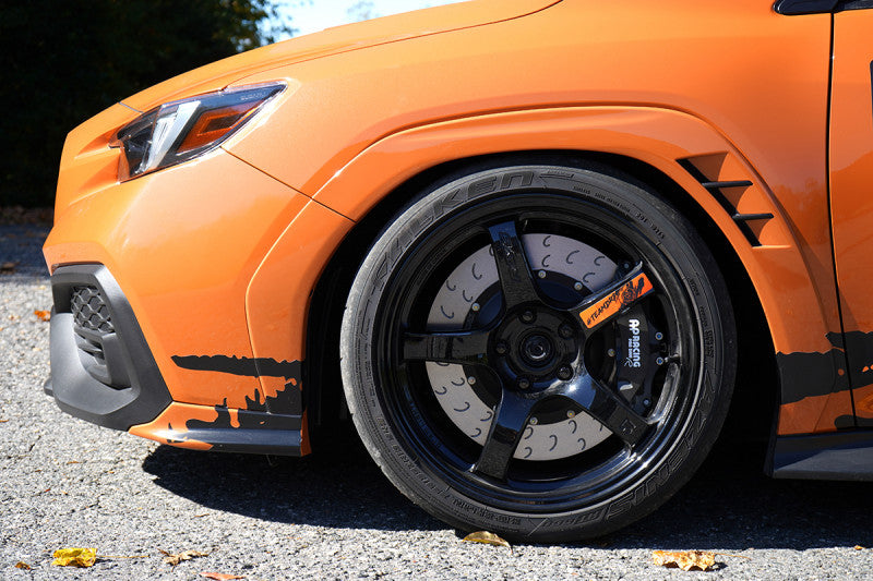 A side close up view of an orange Subaru and its wheel fitted with AP Racing by Essex Radi-CAL ENP Competition Brake Kit (Front CP9660/372mm) - 2022+ Subaru WRX VB