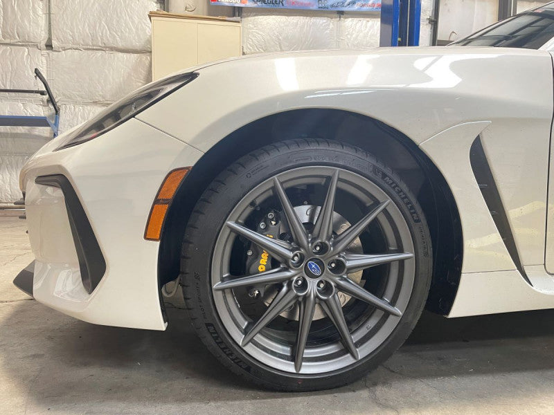 A close up view of a white car with the front wheel fitted with AP Racing by Essex Competition Sprint Brake Kit (Front CP8350/299mm)- Subaru BRZ & Toyota GR86 2022+