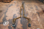Wide top-down view of the complete full-length gold-finished Valvetronic exhaust system laid out on a workshop floor.
