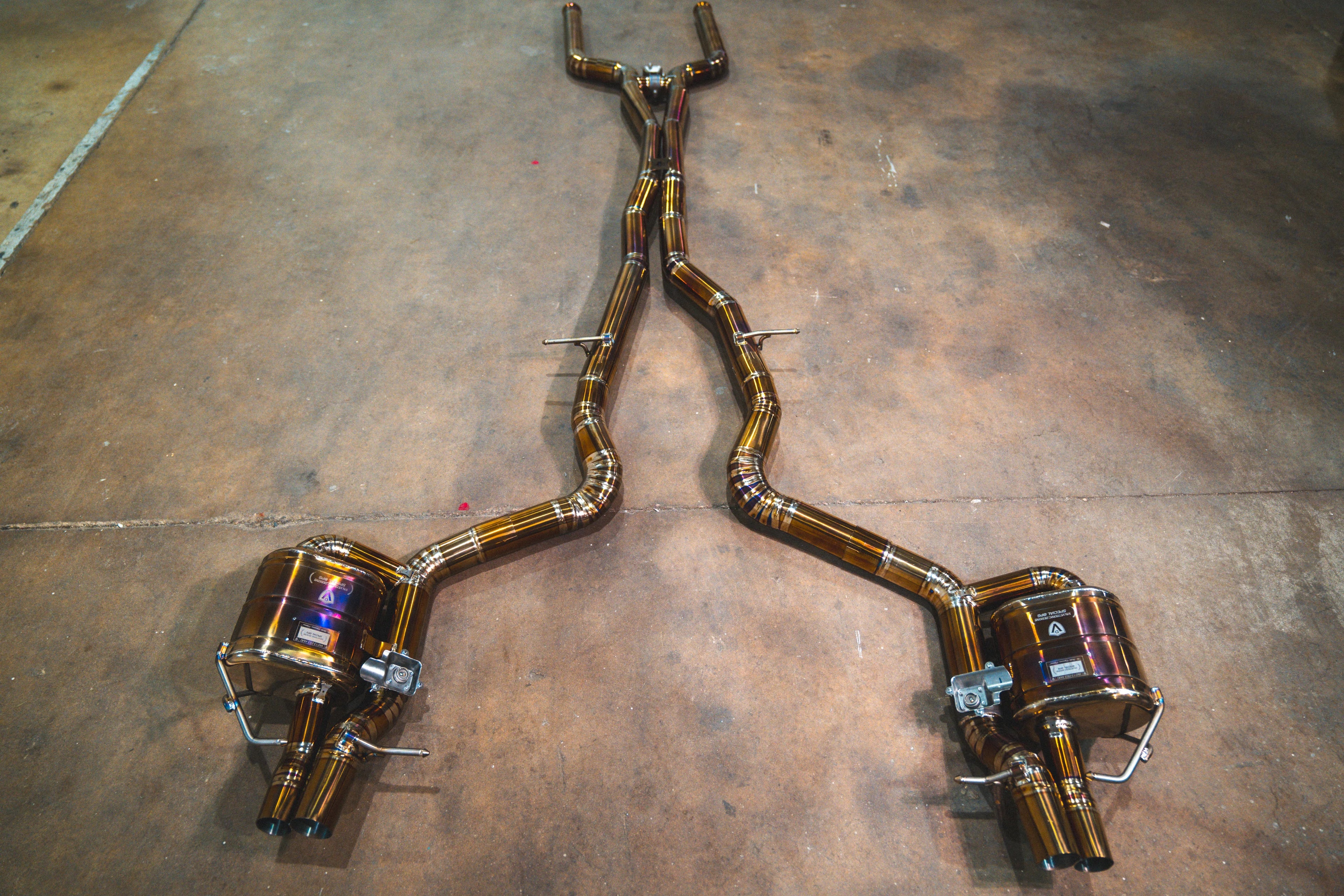 Full overhead view of the complete Valvetronic valved sport exhaust system laid out on a concrete floor.