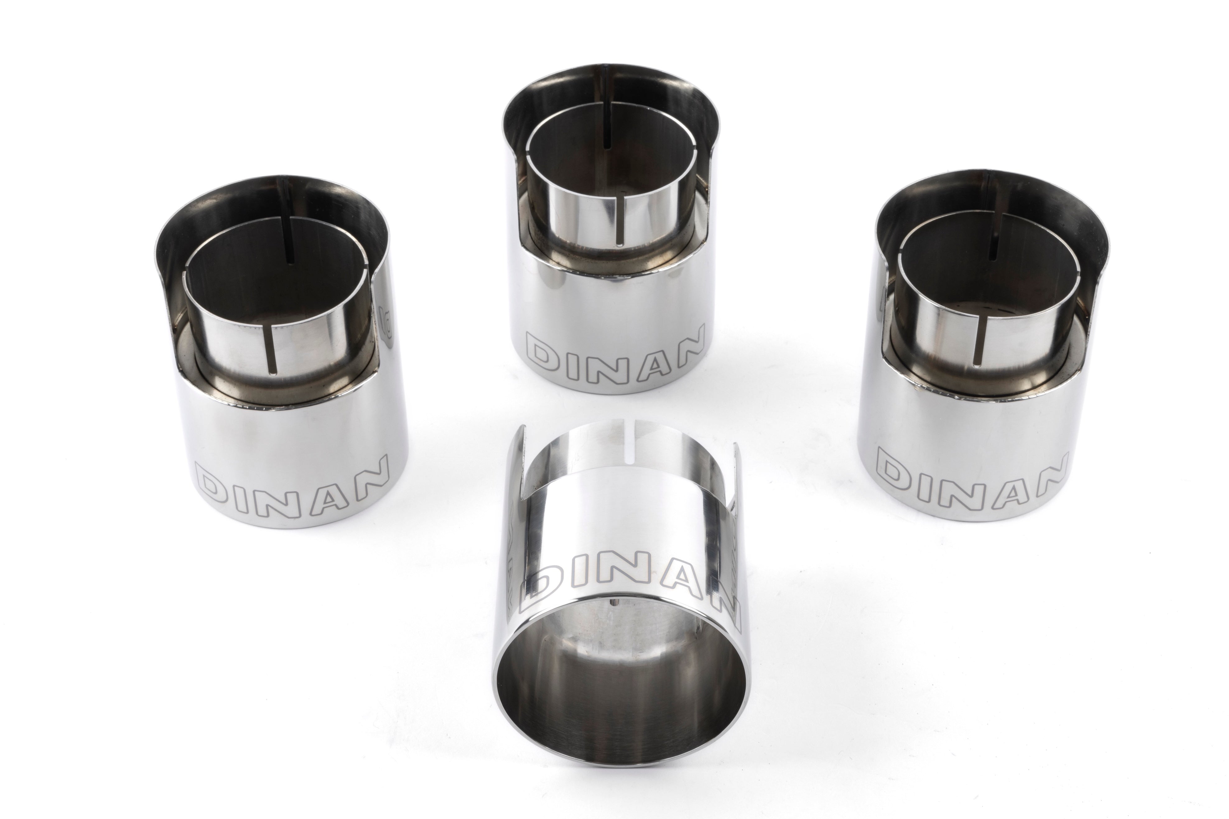 A close-up view of the rear section of the Dinan exhaust system, highlighting the M-inspired quad 3.75-inch double-walled tips. The tips feature a black ceramic-coated finish with laser-engraved Dinan logos. 