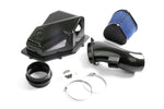 Complete Dinan cold air intake kit components laid out, including the carbon fiber airbox lid, intake tube, high-flow blue conical filter, silicone couplers, and stainless steel mounting hardware.