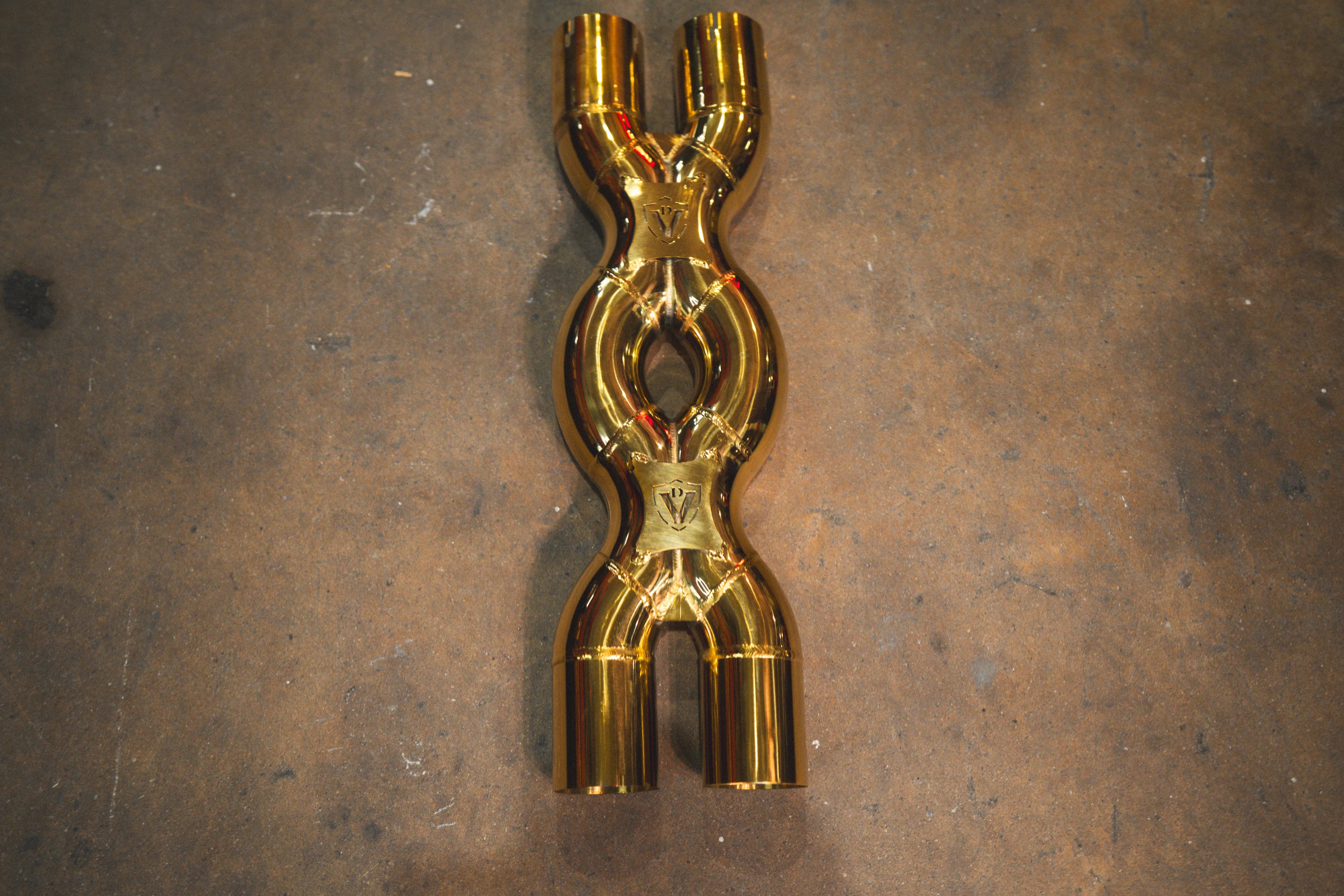A top-down view of the gold-plated X-pipe section featuring two engraved Valvetronic Designs logos.