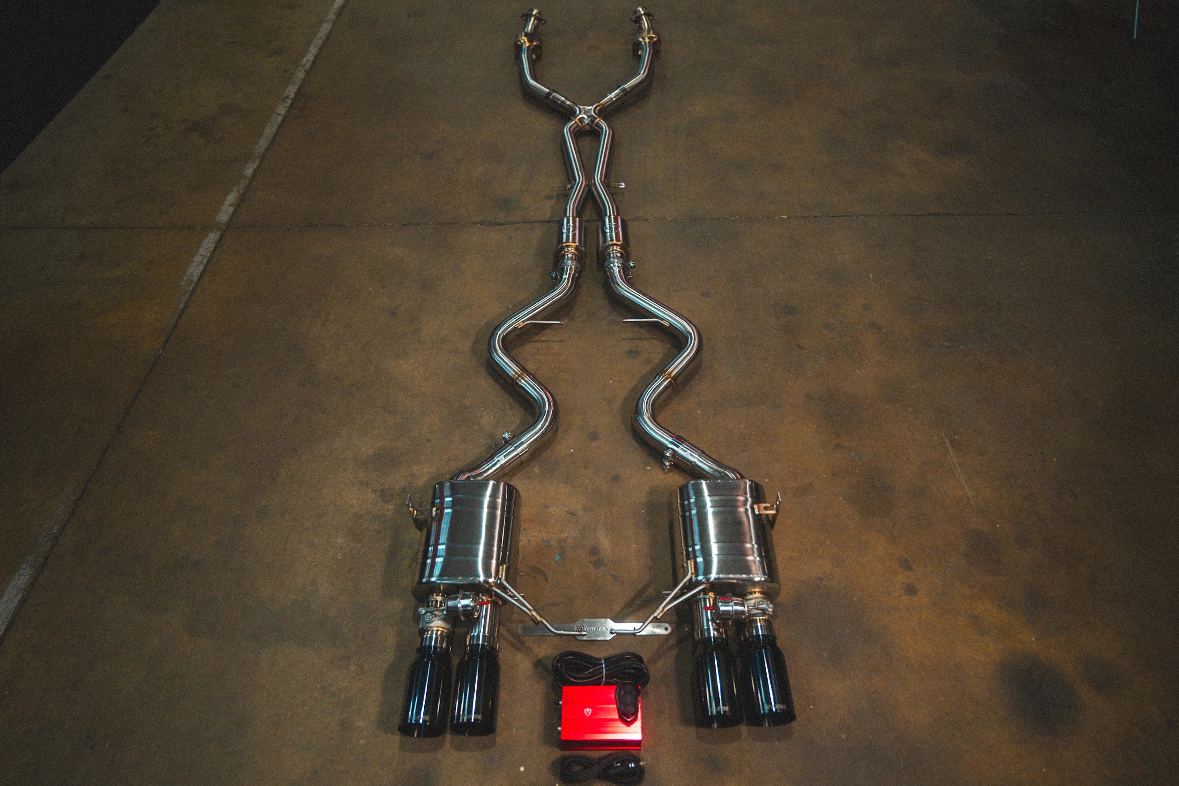 Full view of the Valvetronic Designs Valved Sport Exhaust System for BMW E9x M3 featuring quad gloss black exhaust tips and a red valve control module.