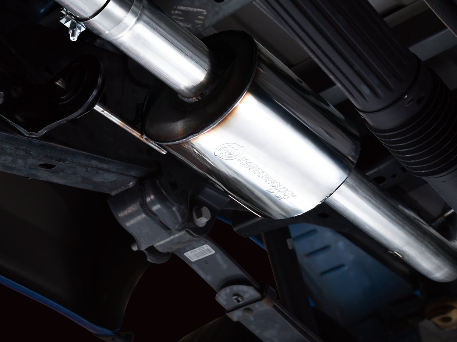 Close underside view of the AWE 0FG stainless pipework running past the F-150 spare tire