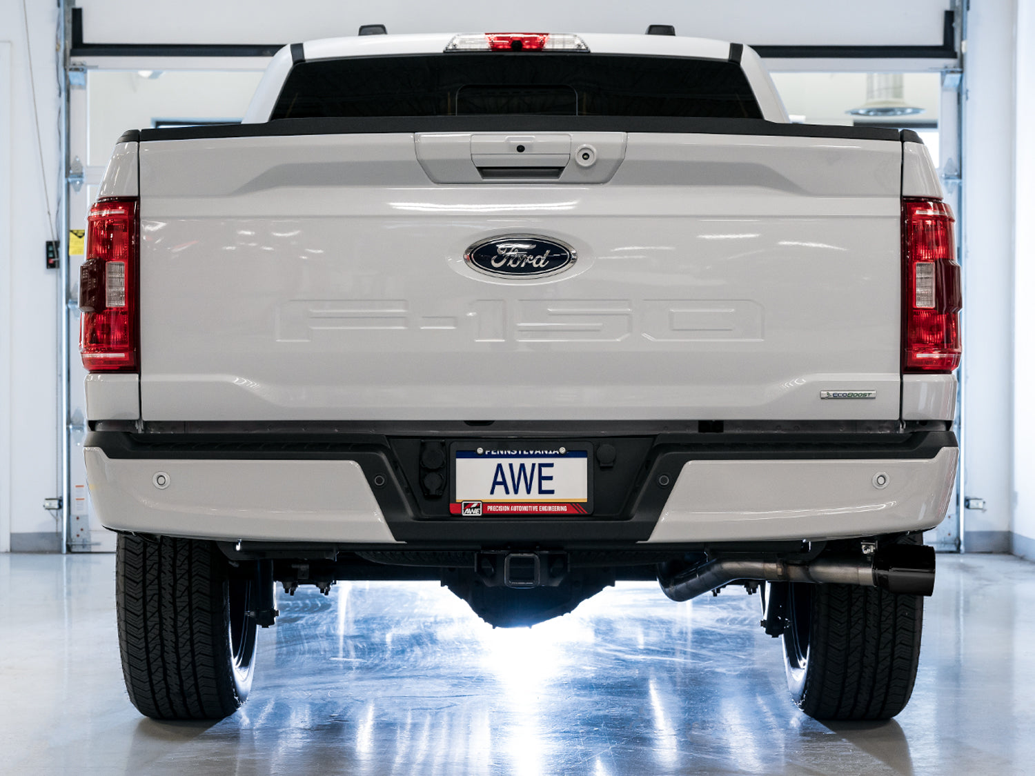 Rear view of a white F-150 in a studio fitted with the AWE 0FG Diamond Black side exit