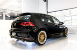 Black Mk7 GTI with gold wheels, rear three-quarter studio view with AWE exhaust tips
