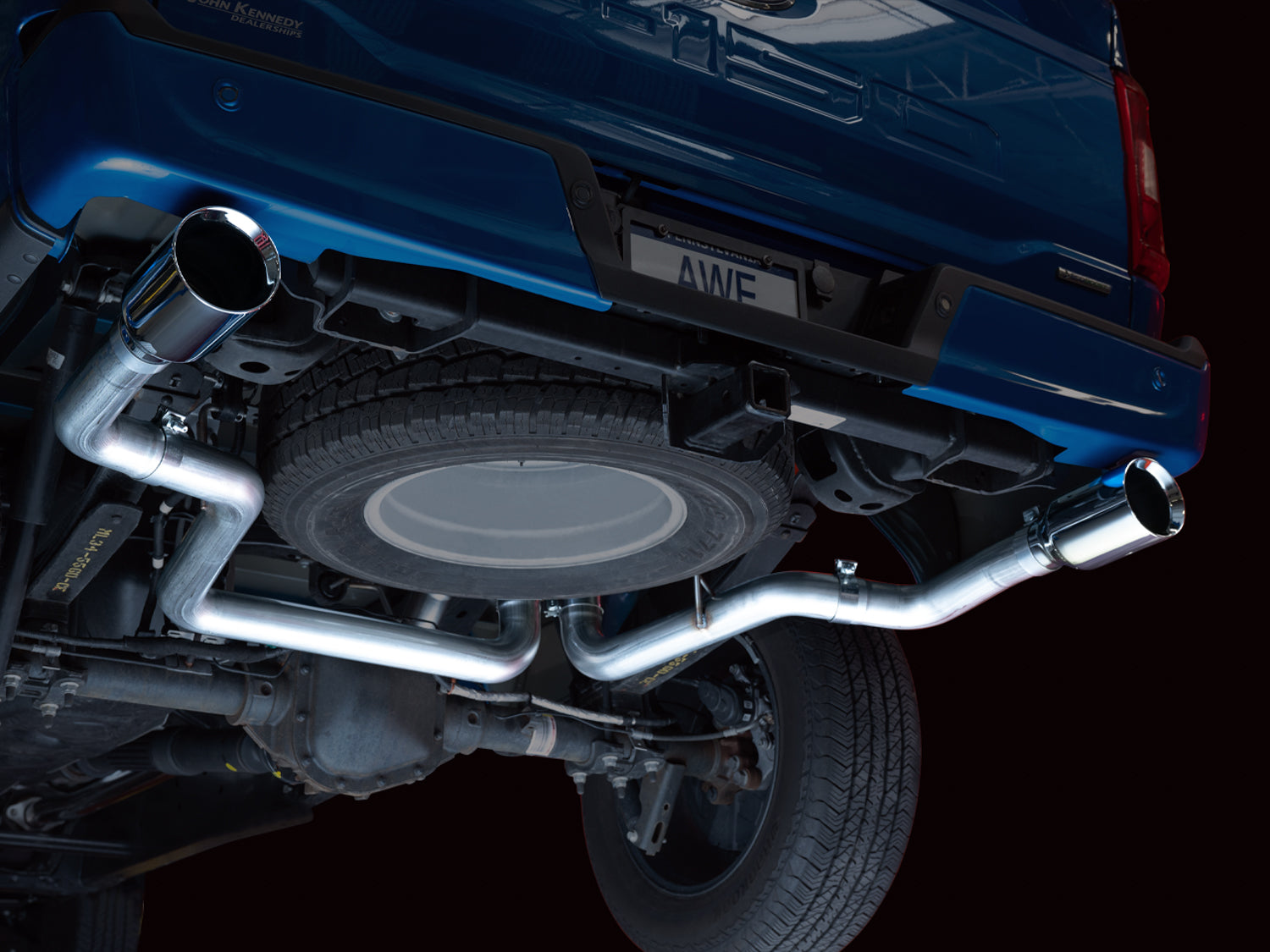 Low underside view of the AWE 0FG split rear pipes routed around the F-150 spare tire
