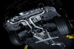 Underside of an A90 Supra on a lift showing AWE Track Edition pipework routed to the rear