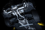 Underside of a GR Supra on a lift showing the AWE Touring mufflers and twin mid pipes