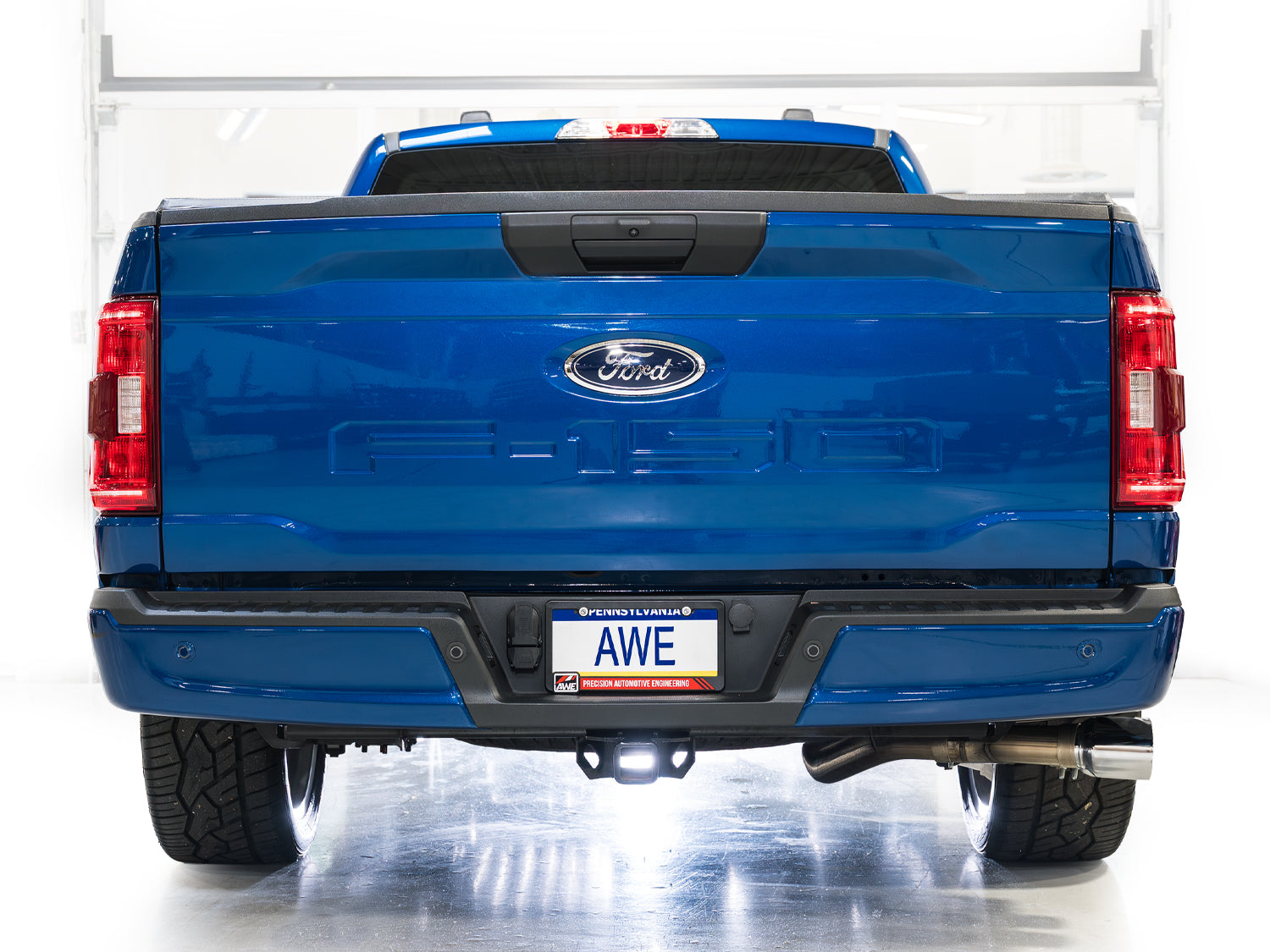 Rear view of a blue F-150 Regular Cab in a studio fitted with the AWE 0FG exhaust