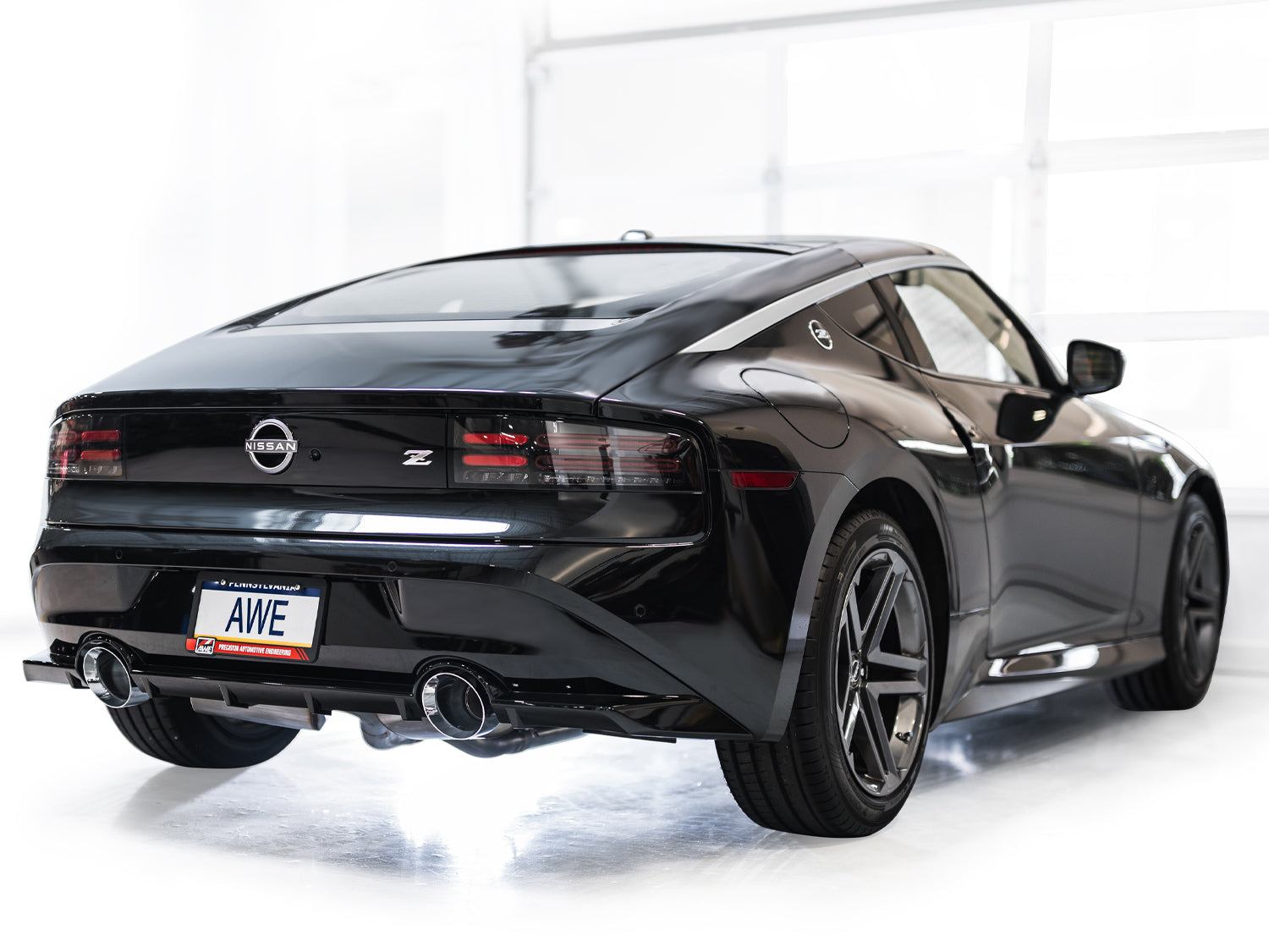 Black Nissan Z rear three-quarter view in a studio with AWE chrome Touring tips