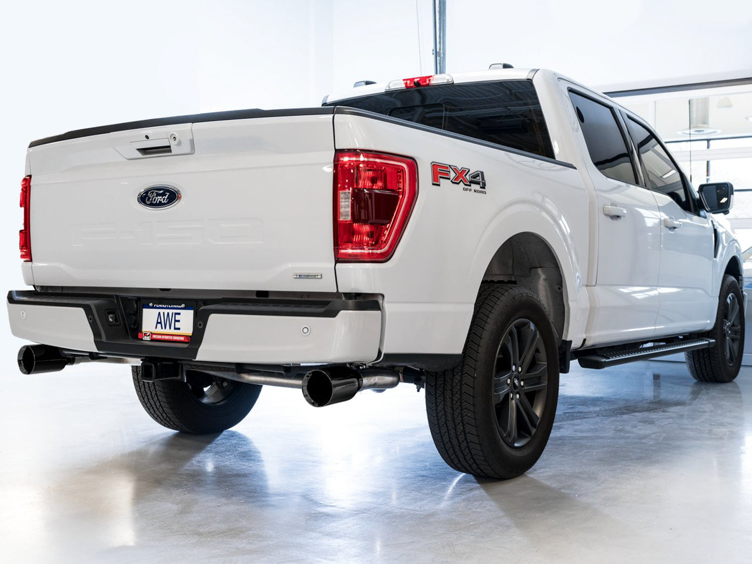 White F-150 rear three-quarter view fitted with AWE 0FG Diamond Black split rear tips