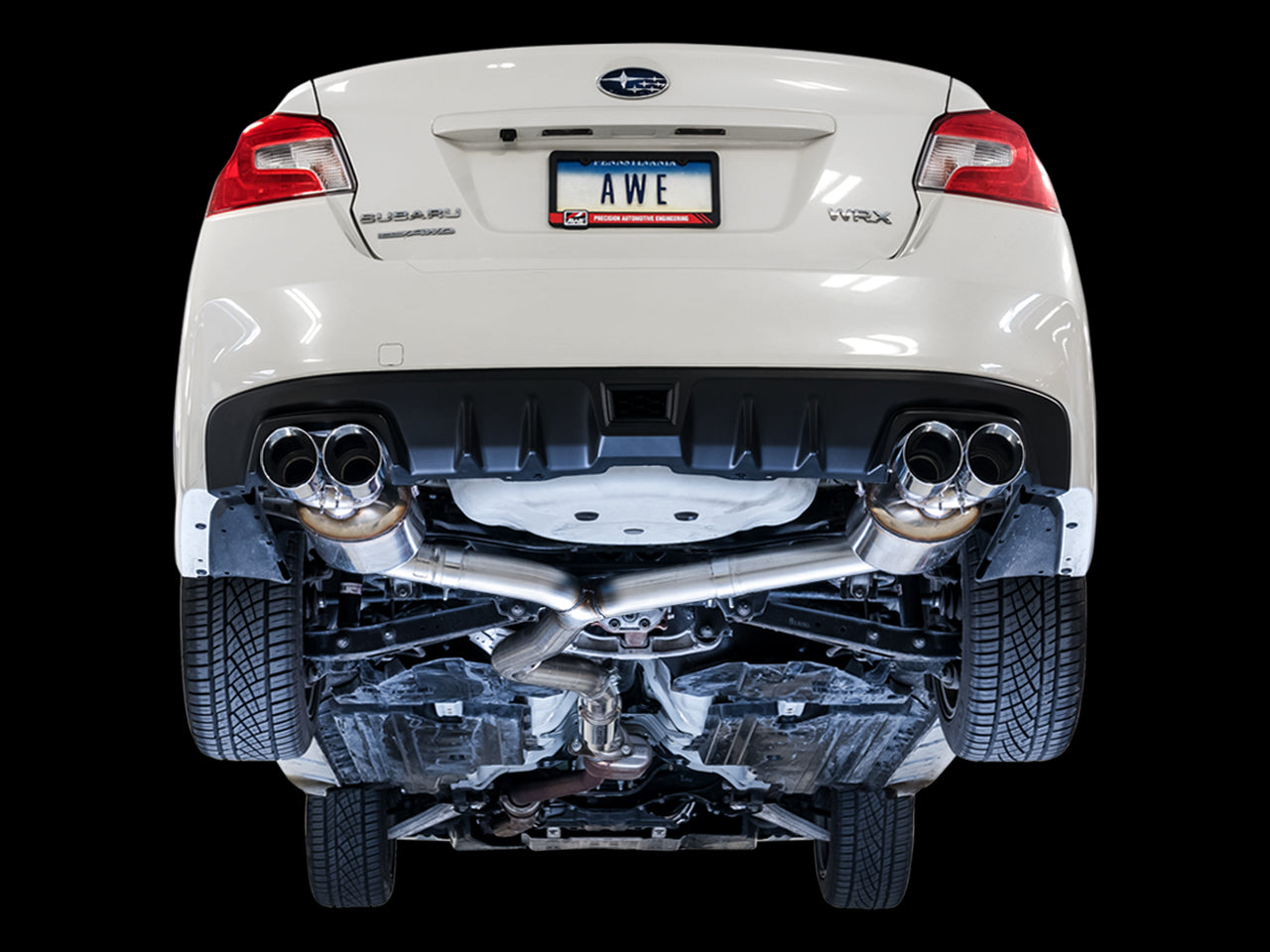 Underside of a white WRX sedan on a black backdrop showing the AWE Touring pipe routing