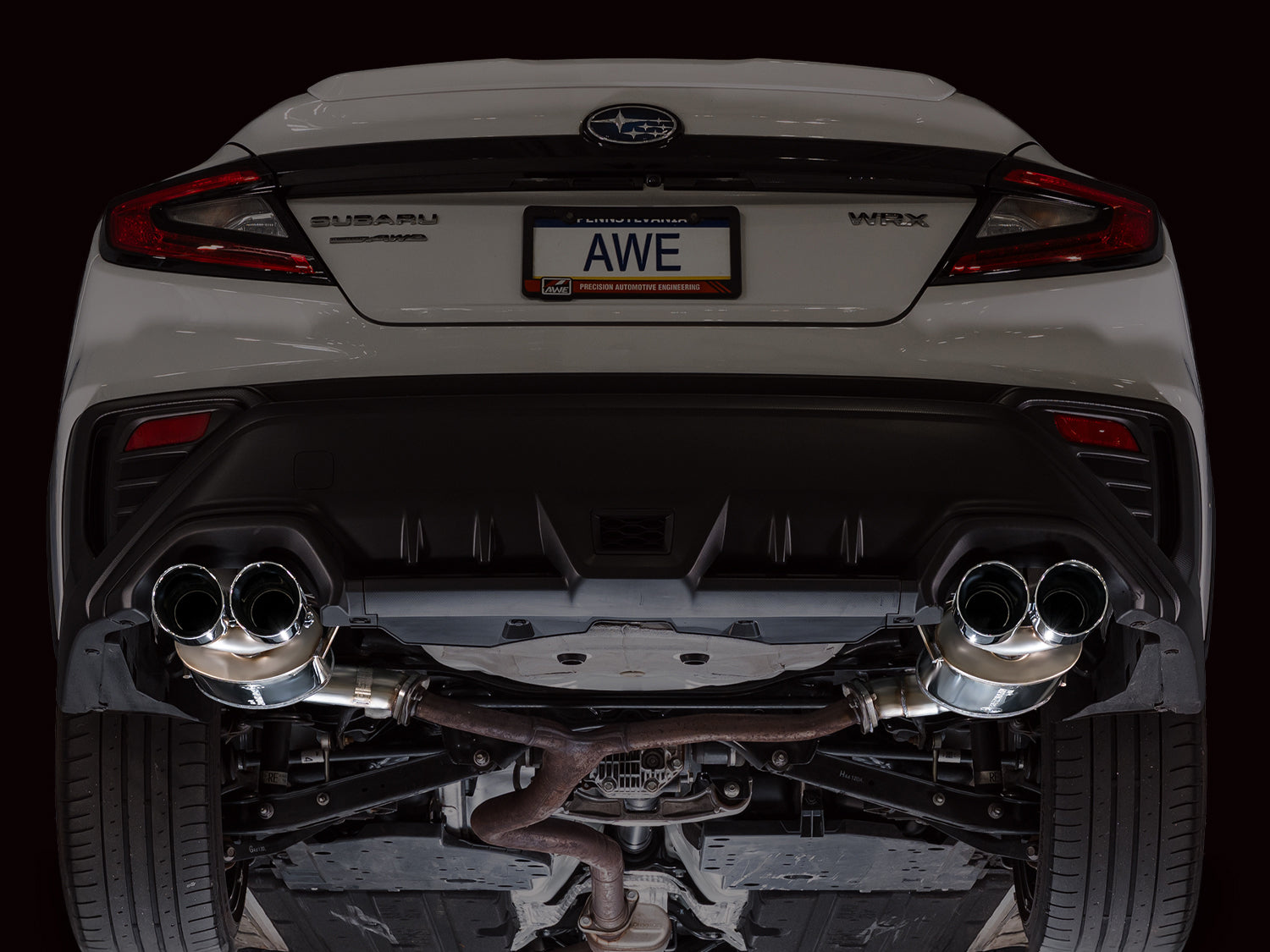 Rear of a white VB WRX on a lift showing the AWE Touring axle-back and quad tips