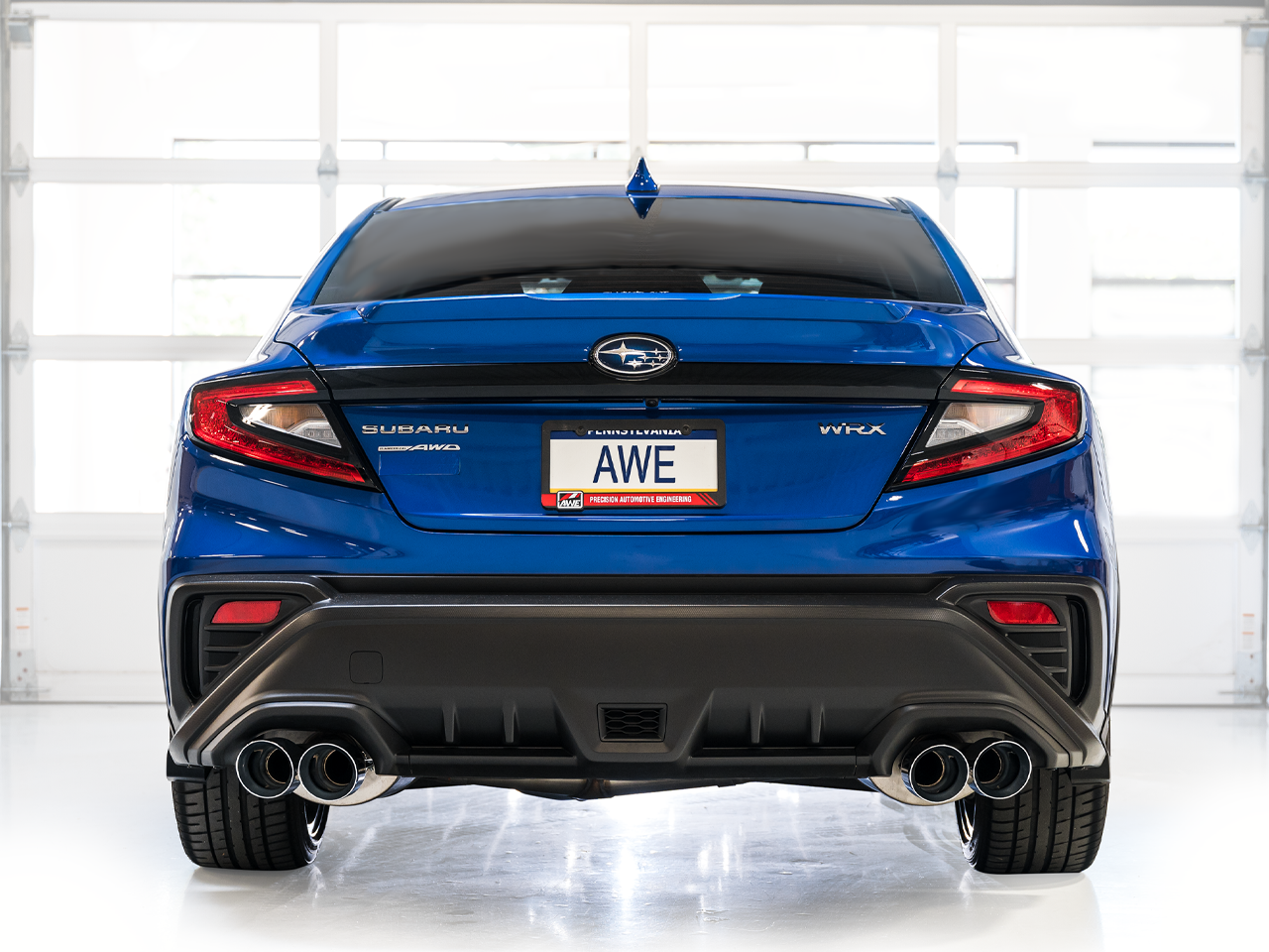 Blue VB WRX rear view in a white studio with quad AWE exhaust tips under the bumper