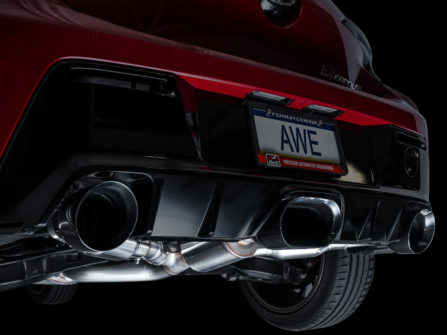 Red GR Corolla rear bumper close-up with AWE Diamond Black oval and round tips
