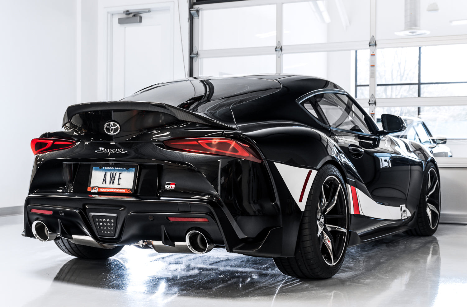 Black GR Supra rear three-quarter in a studio showing AWE Non-Resonated Touring tips