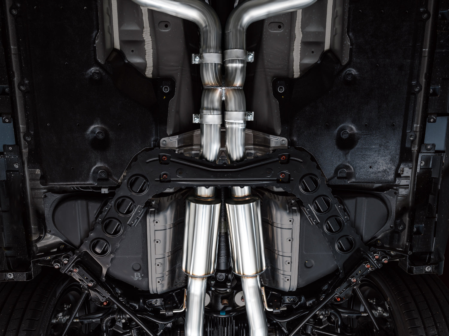 Overhead underbody view of the AWE Track dual 3-inch pipes leaving the Nissan Z downpipes