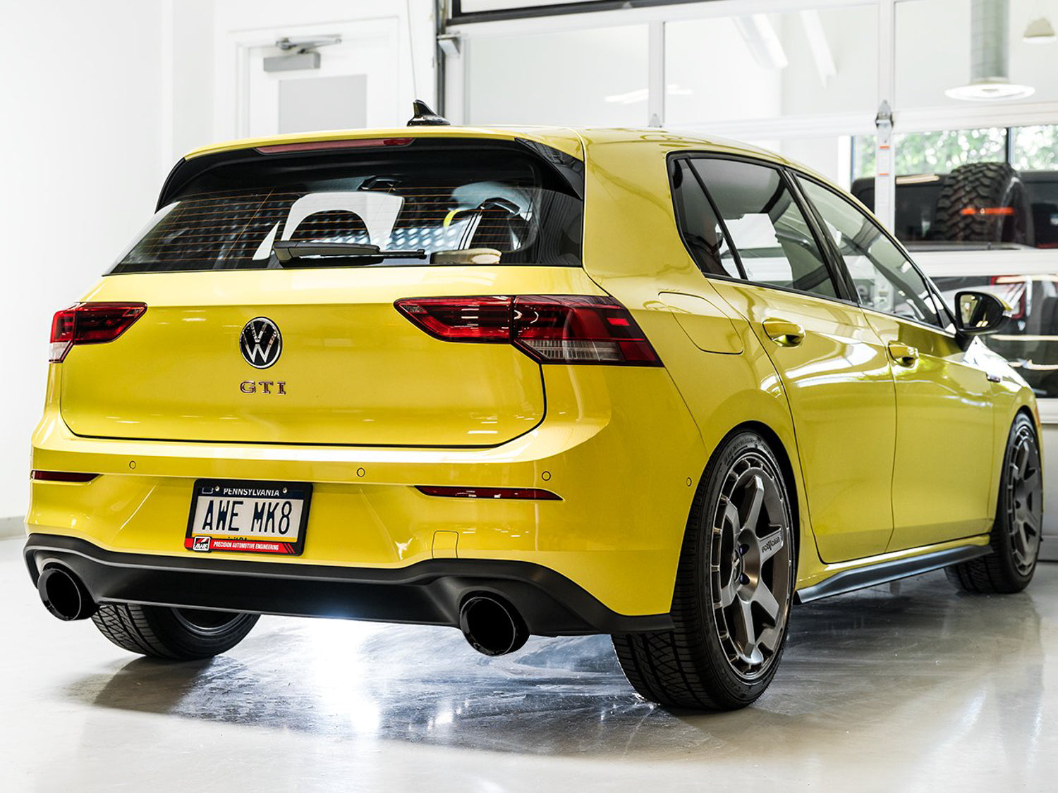 Rear three-quarter view of a yellow Mk8 GTI with AWE Track Edition Diamond Black tips