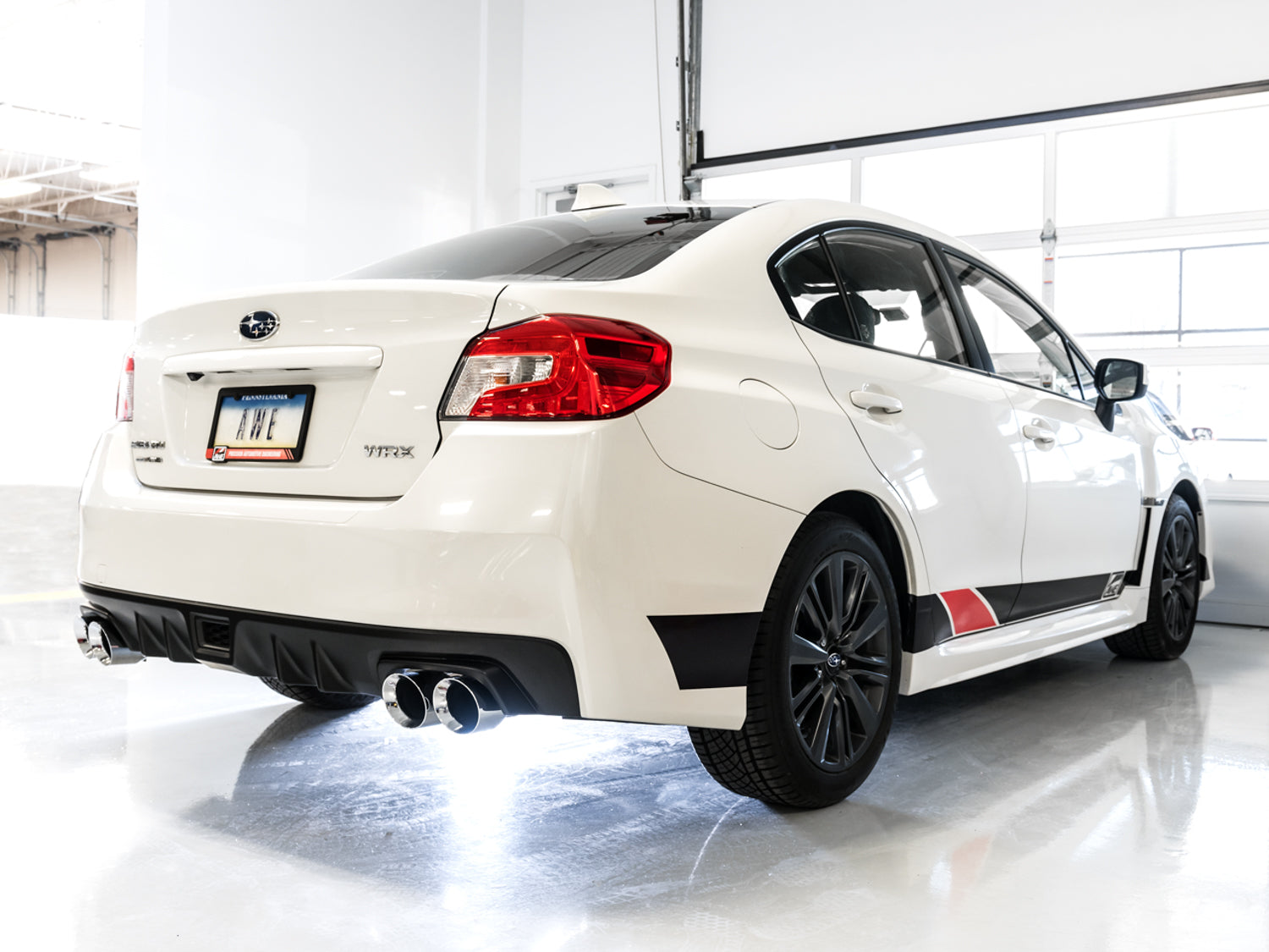 White VA WRX rear three-quarter in a studio fitted with AWE Track chrome quad tips