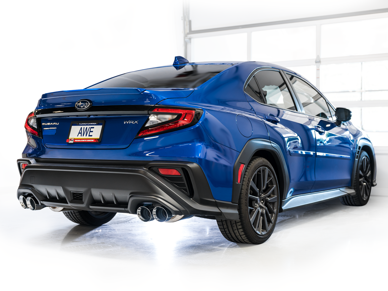 Rear three-quarter view of a blue VB WRX in a white studio with AWE Track Edition tips