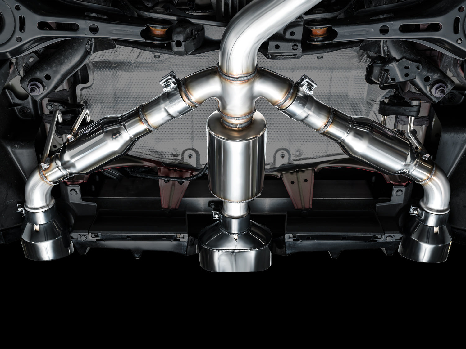 Underbody view from behind of the AWE Track tri-merge splitting into three outlets