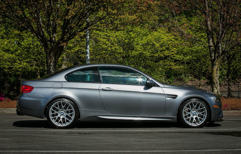 A wide side view of a grey BMW car with its wheels fitted with AP Racing by Essex Radi-CAL ENP Competition Brake Kit (Front 9660/372mm)- BMW E90/E92/E93 M3 & 1M Coupe