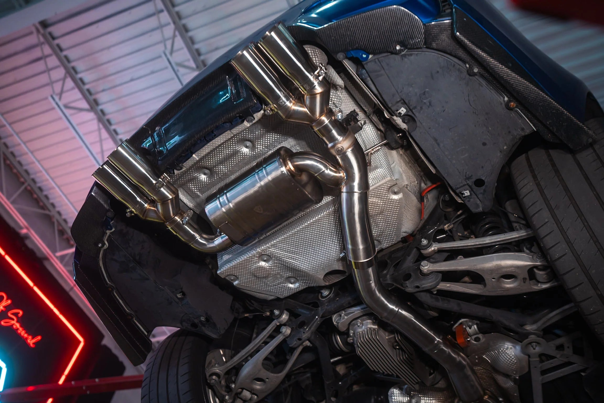 The exhaust system installed on the undercarriage of a BMW M3/M4, showing the muffler and quad tips.
