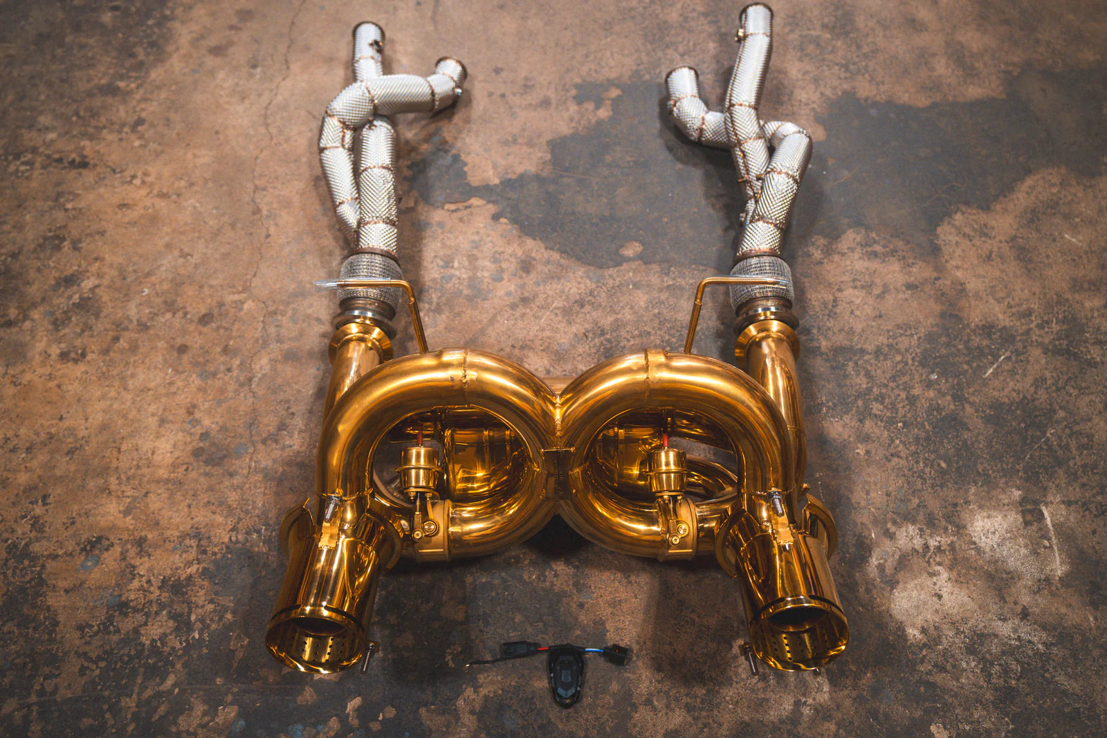 Full overhead view of the complete gold exhaust assembly including the valved muffler section and two long silver heat-shielded intake pipes.