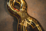 A close-up, angled shot of the gold-plated X-pipe focusing on the welded joints and the engraved shield logo.
