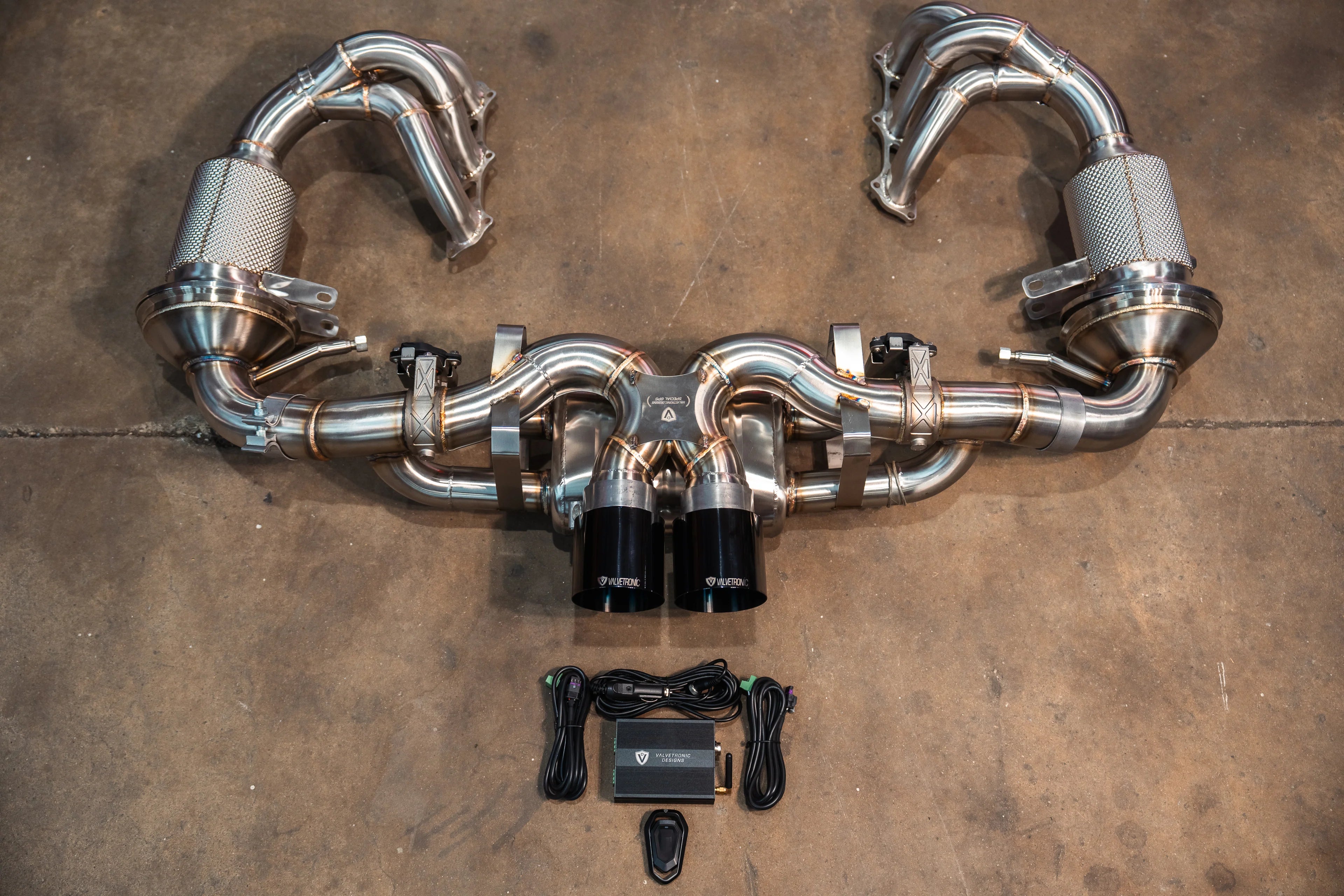 Top-down view of the full exhaust system including the valved center muffler, high-flow headers with mesh-wrapped sections, and the electronic control kit.