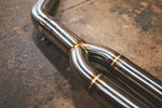 A close-up of the Y-pipe transition on the stainless steel exhaust, highlighting the uniform TIG welds and the smooth split into two parallel pipes.