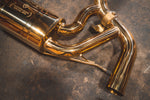 Detail shot of the polished gold muffler casing featuring the Valvetronic Designs engraved logo and connecting mandrel-bent pipes.