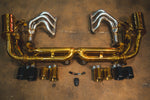 Overhead view of the gold-finish exhaust system with the addition of silver-finish performance headers positioned above the muffler assembly.